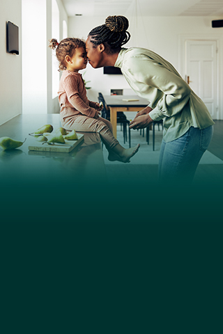 Woman playing with child in kitchen.