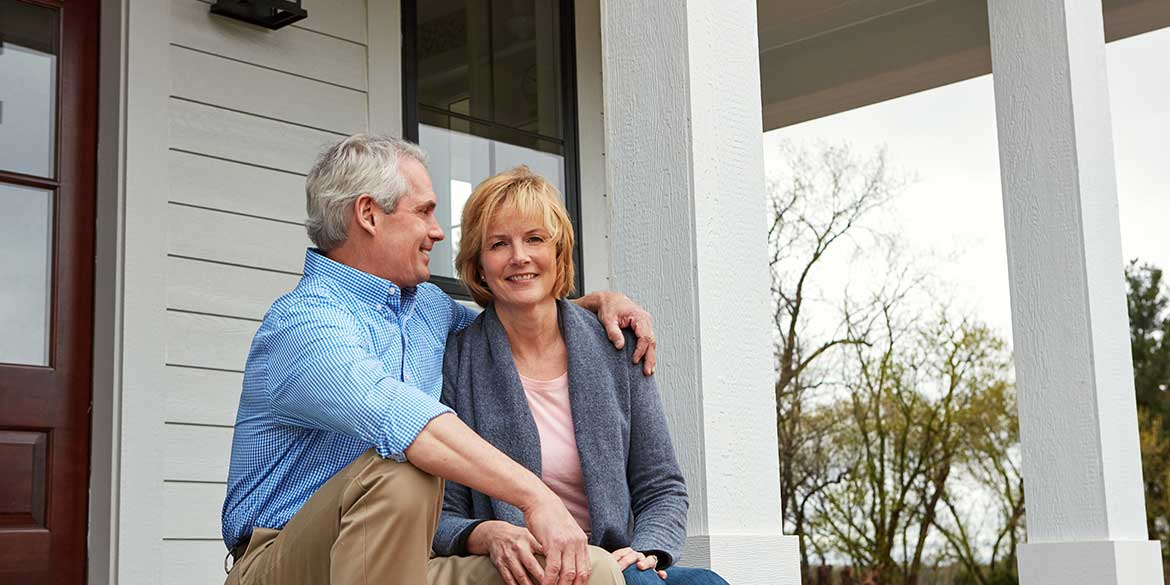 Baby Boomer Couple Sitting on Porch Embracing