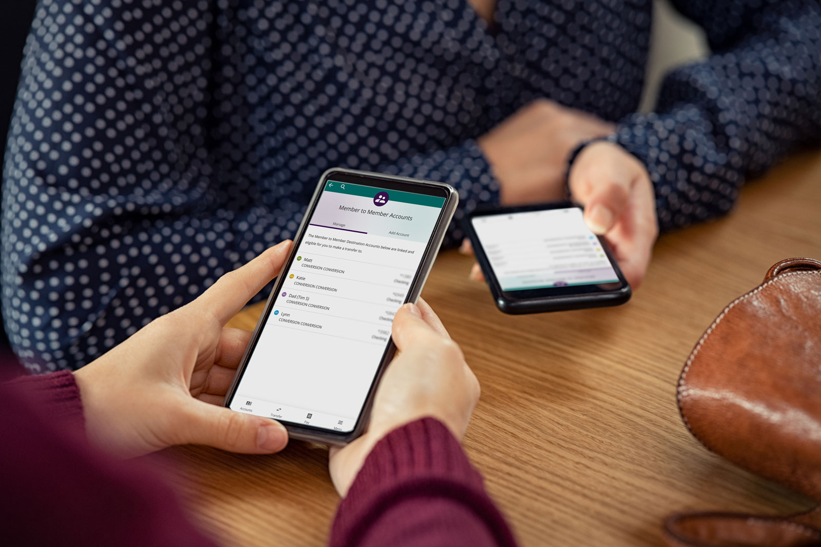 Two people holding cell phones with Community First Digital Banking using member to member money transfers.