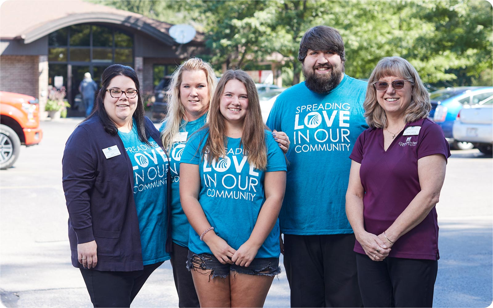 Community First Credit Union team members in teal and blue shirts outside.