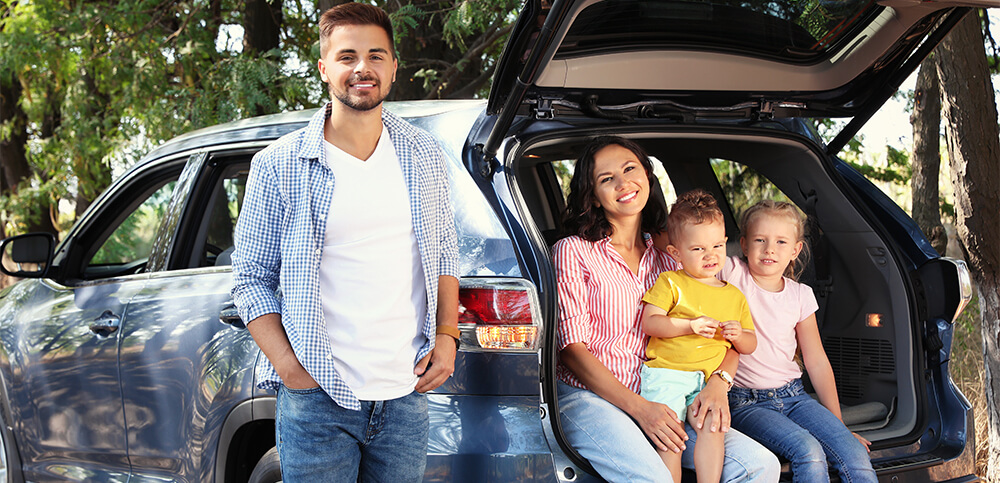 family sitting on the back of a car.