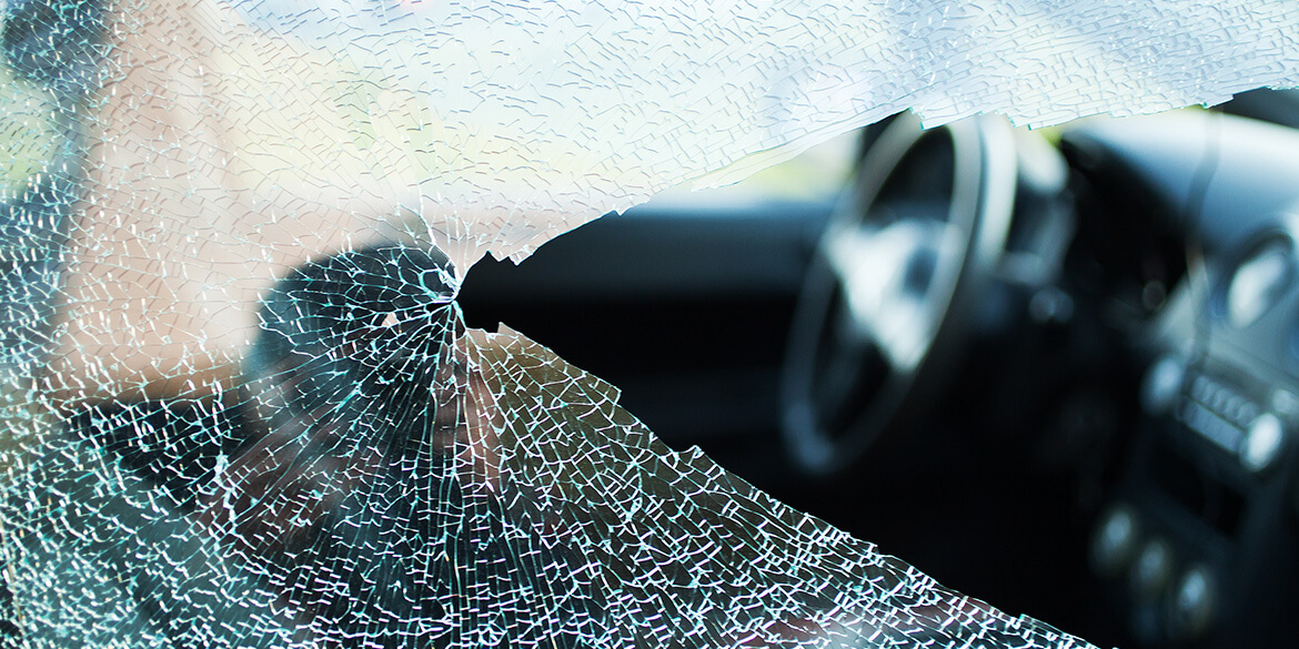 Close up of broken glass with black car interior in background.