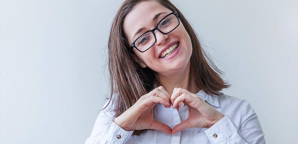 Lady smiling forming a heart with her hands.