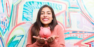 Teen with colorful background holding piggy bank.