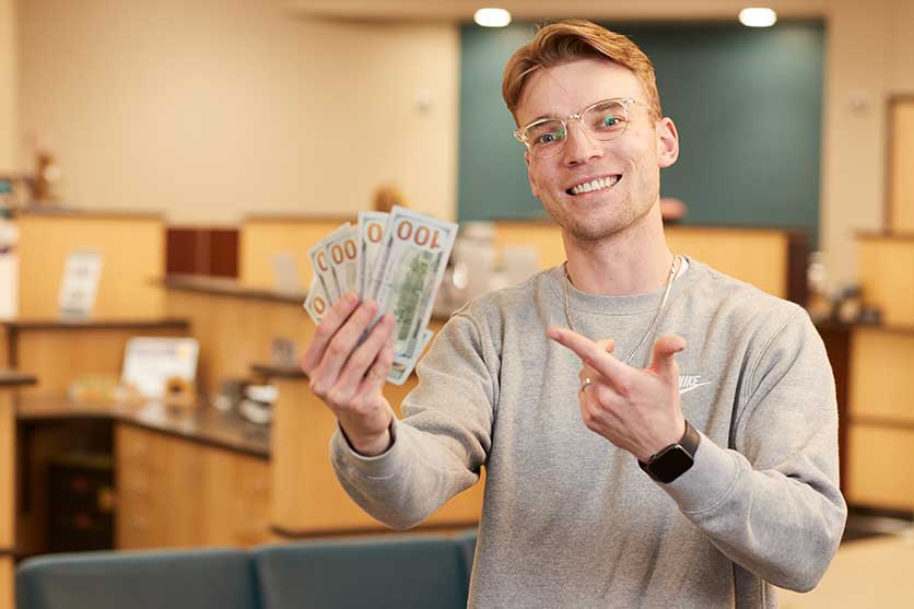 Man holding up $100 bills in a bank for saving and money markets