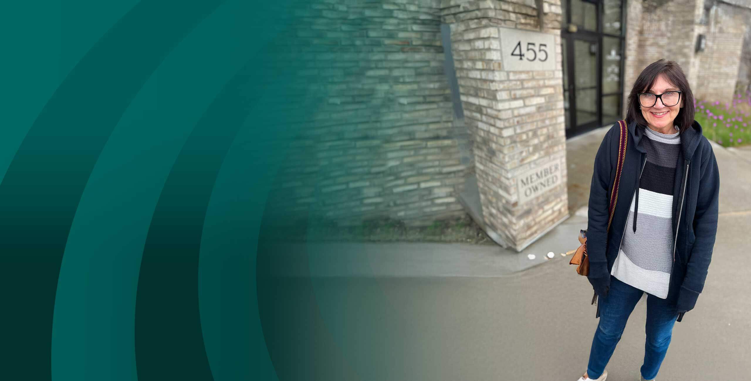 Woman standing outside our building next to Member Owned engraving