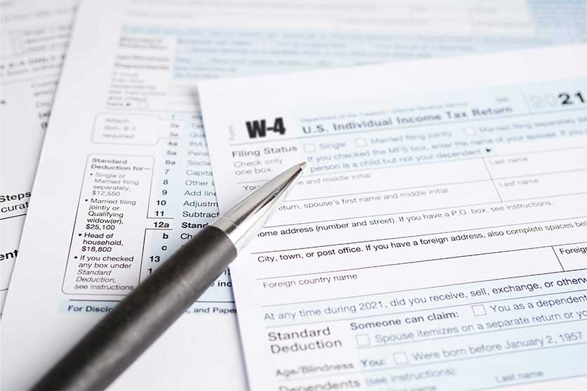 pen on papers filling out W-4 tax forms