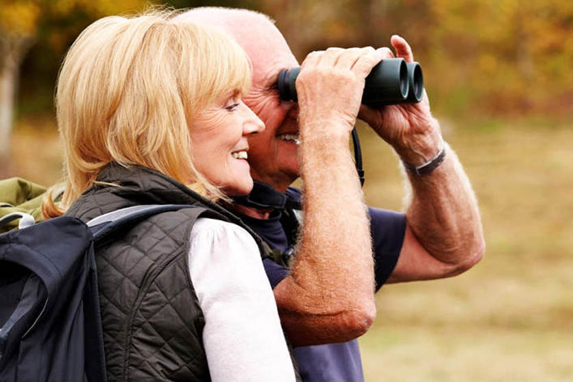 Man and woman with binoculars outside.