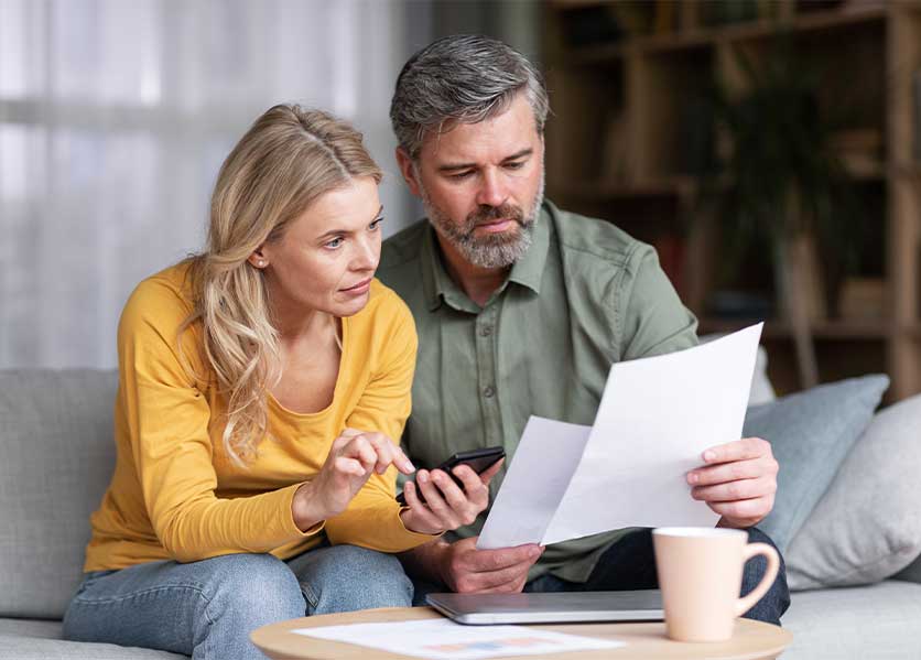 Couple on couch reviewing papers.