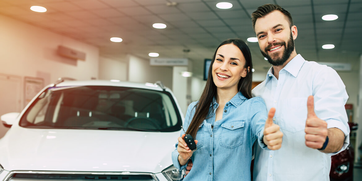 Happy couple at car dealership.