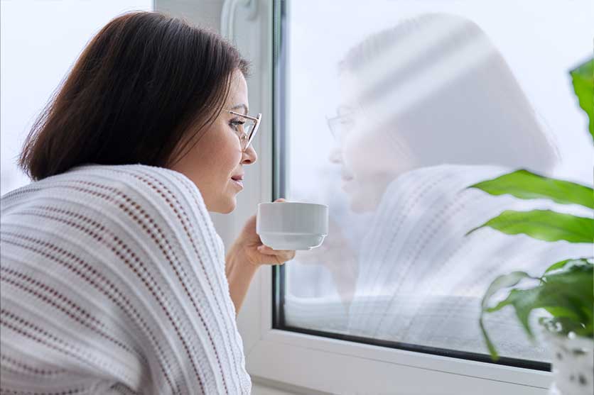 Woman with a cup staring out the window pensively