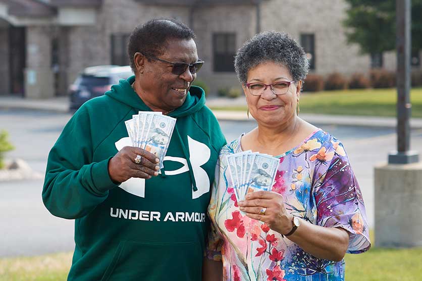 Couple holding up money as they save at Community First Credit Union