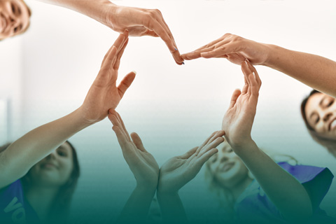 Girls hands in the shape of heart with green background.
