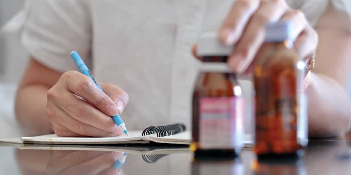 Close up of notepad, pen, and medications.