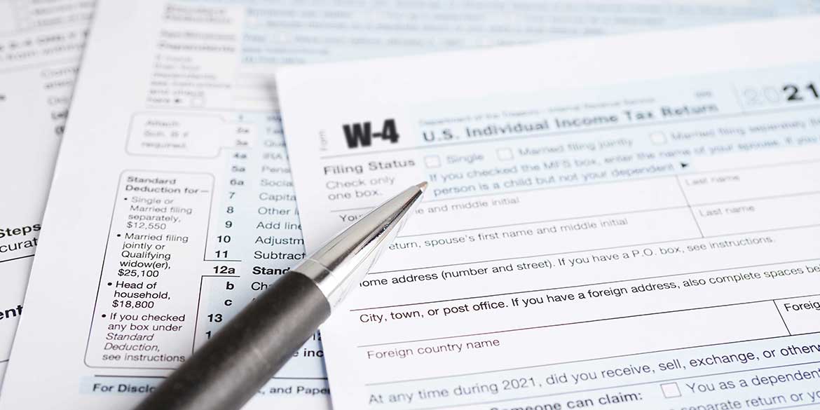 Tax papers with a pen on top to show the need to adjust your tax withholding.