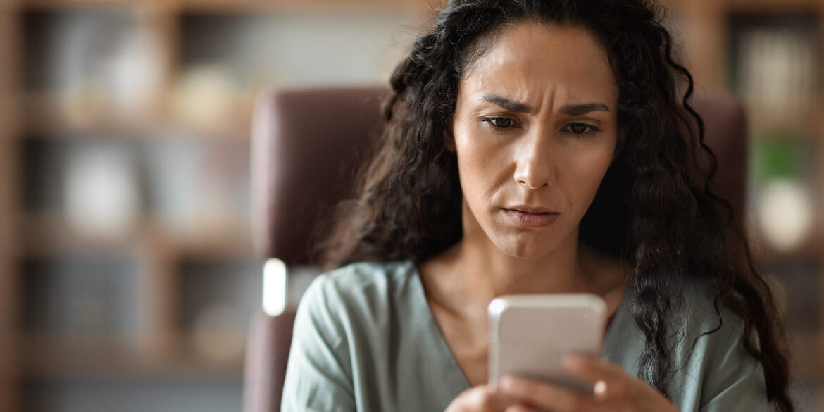 Concerned woman looking at message on cell phone.