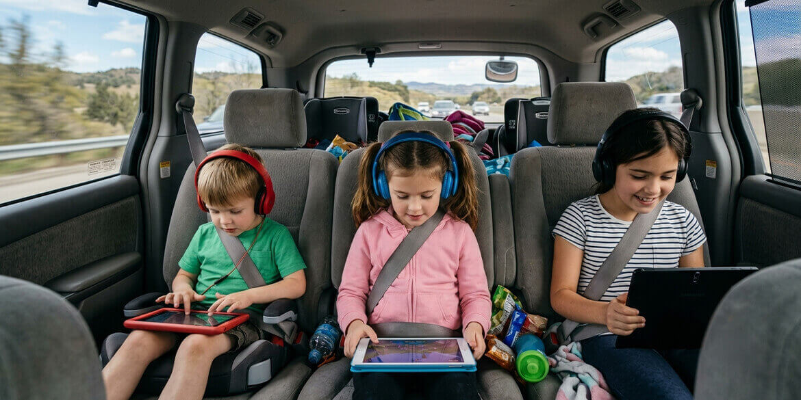 Kids in van on tablets.