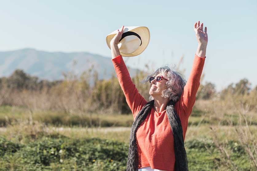Woman with arms raised in mountains.