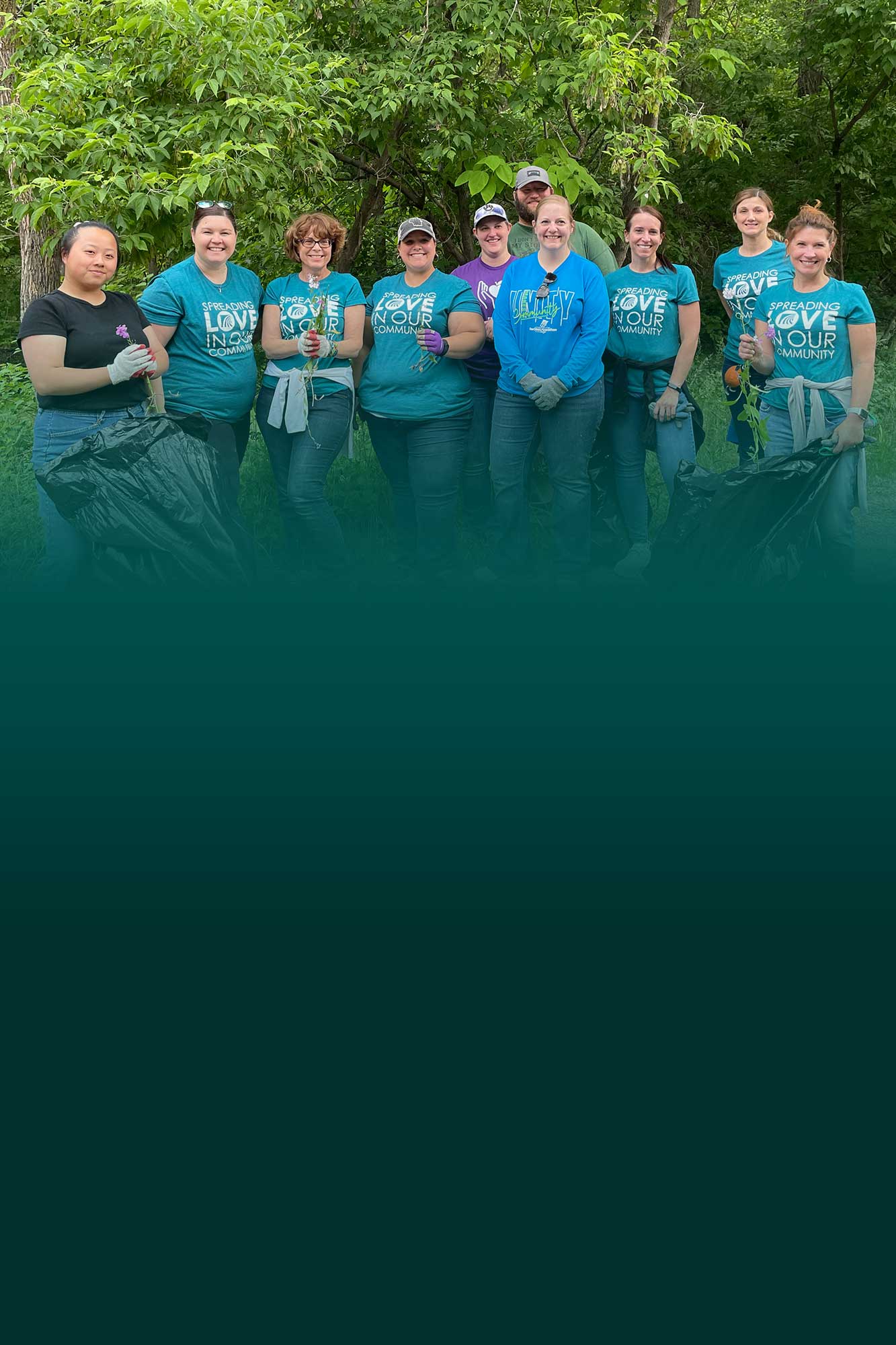 Group of people posing for portrait outdoors collecting trash to keep community clean