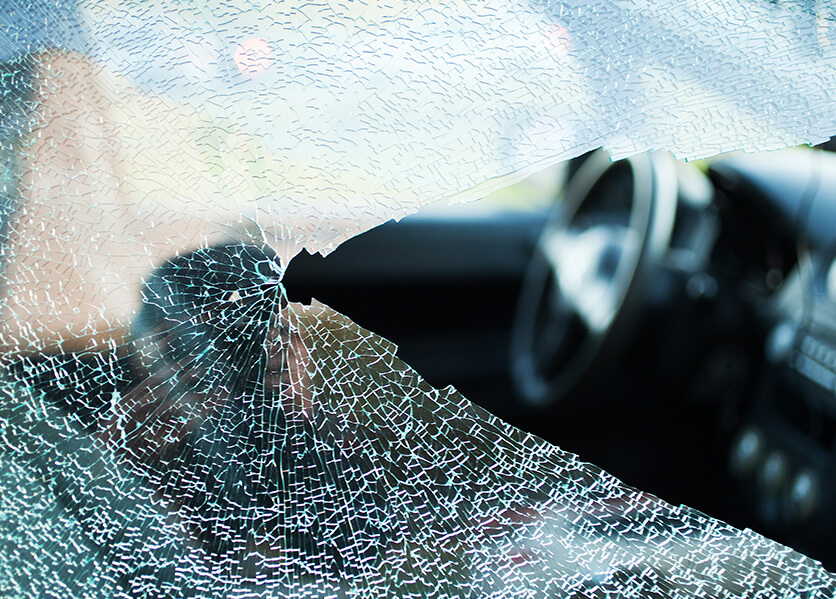 Close up of broken glass with black car interior in background.