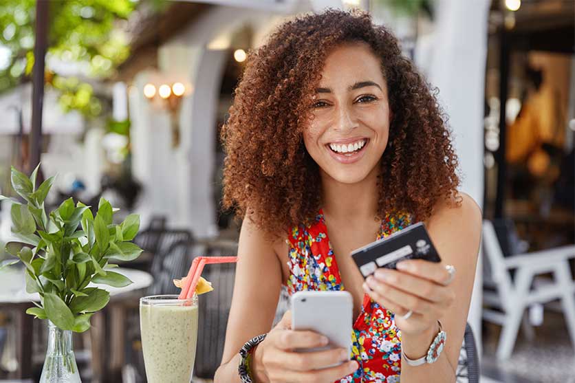 Smiling woman pay for food at restaurant with her Community First Debit Card