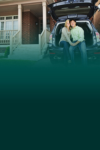 couple sitting in car by house.