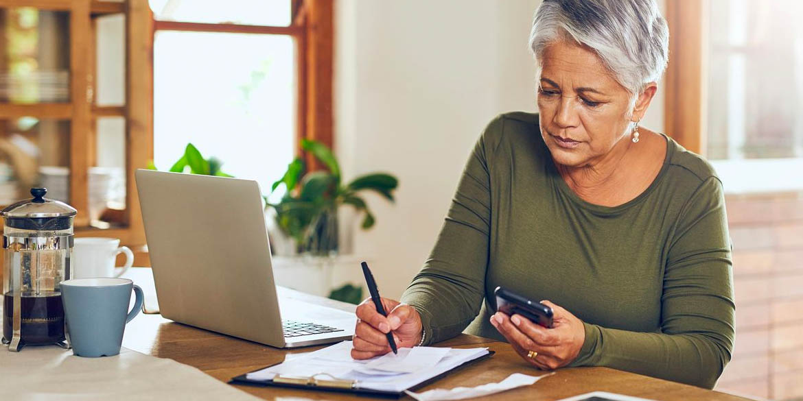 Woman with green shirt with pen phone laptop creating sound retirement plan.