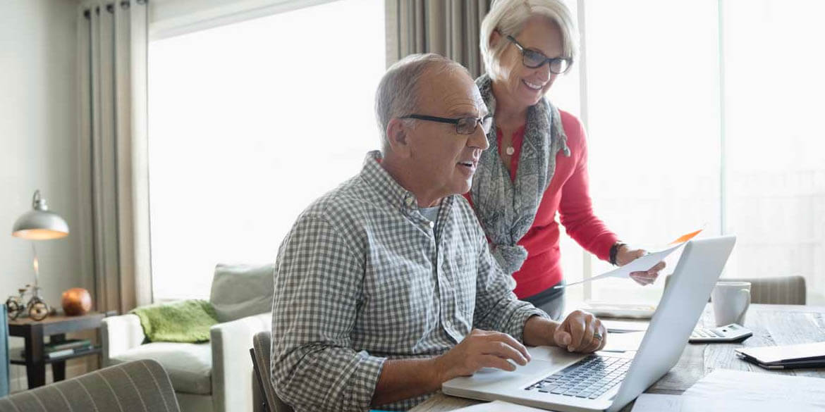 Retired man and woman looking at laptop.