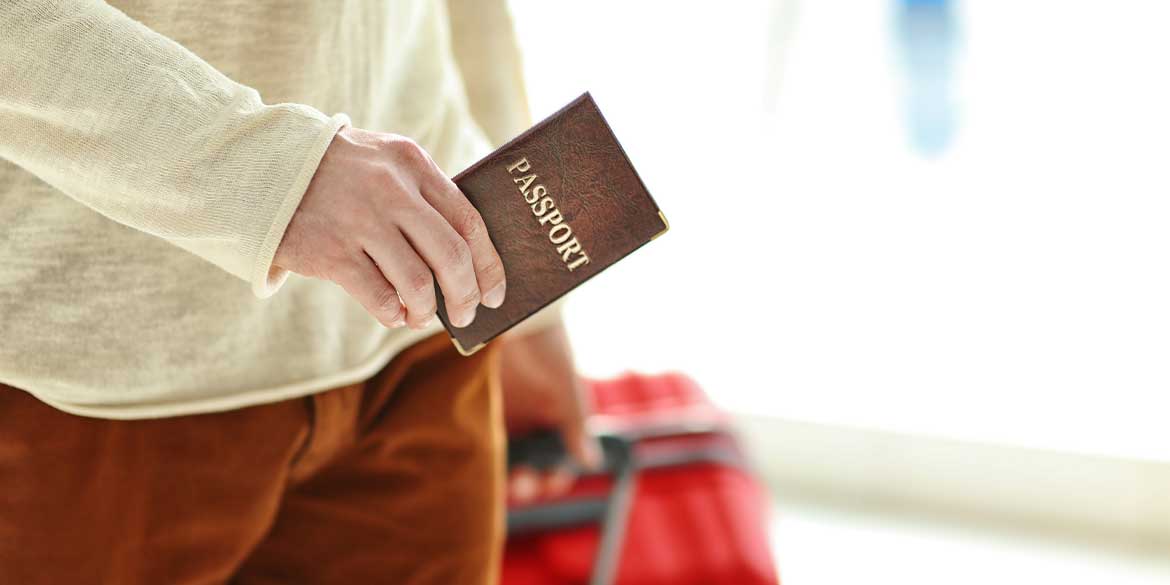 Someone's hand holding a passport as they are about to board a plane for international travel