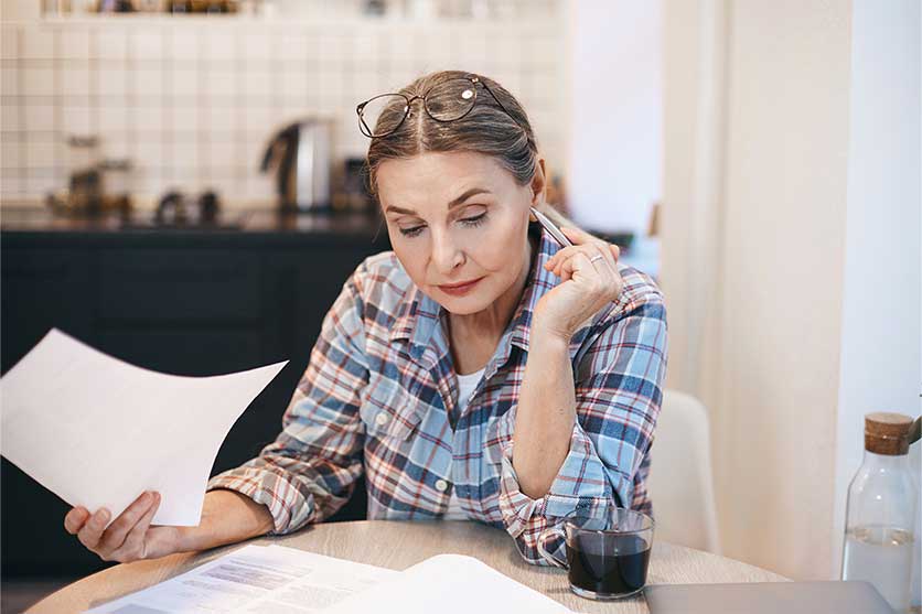 Woman in blue plaid reviewing tax documents.