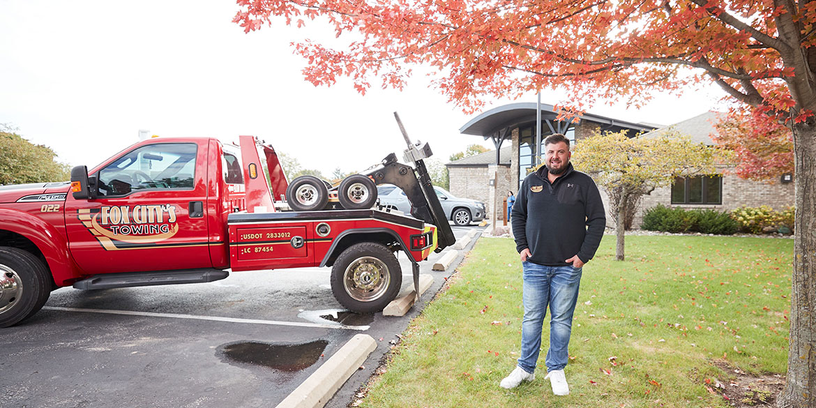 Nick Van standing to the side of his red Fox City's tow truck