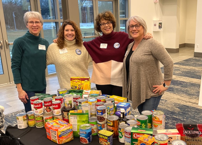 Four females with table full of canned and box food for Salvation Army.