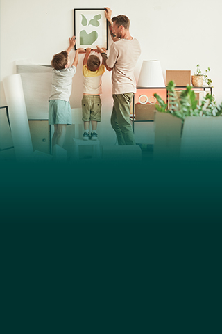 Man and two children hanging art on wall