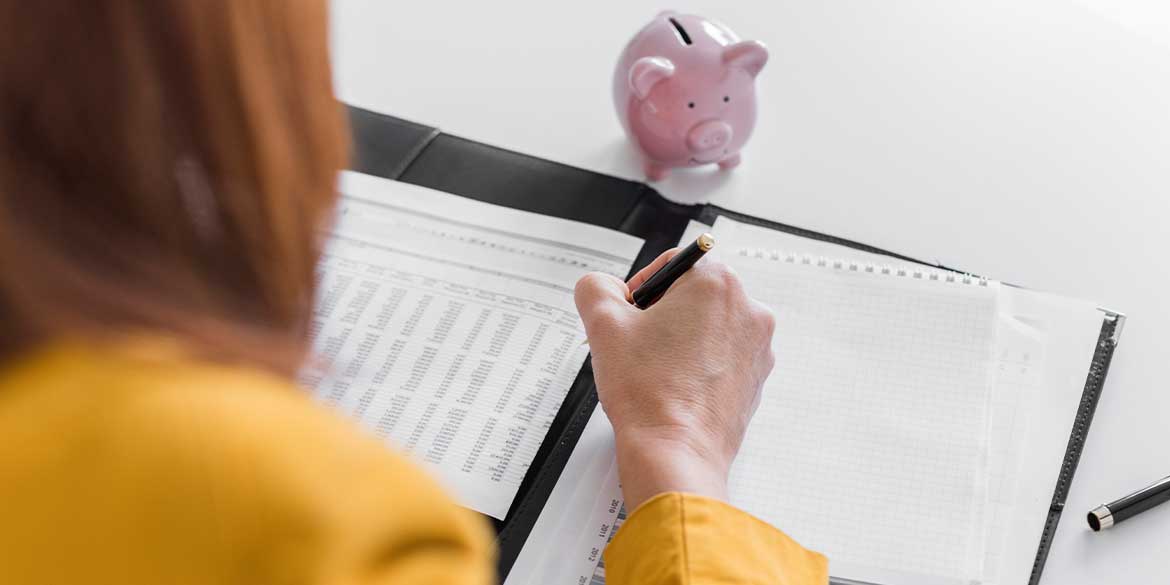 Woman in yellow doing financial planning near piggy bank.