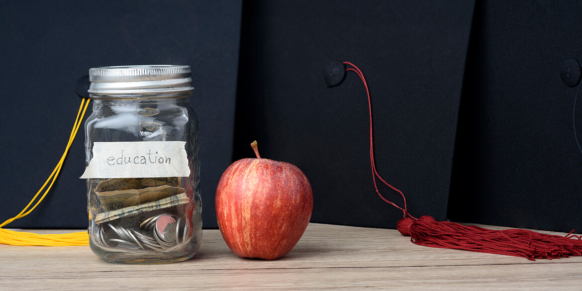 Glass jar with money and grad caps.